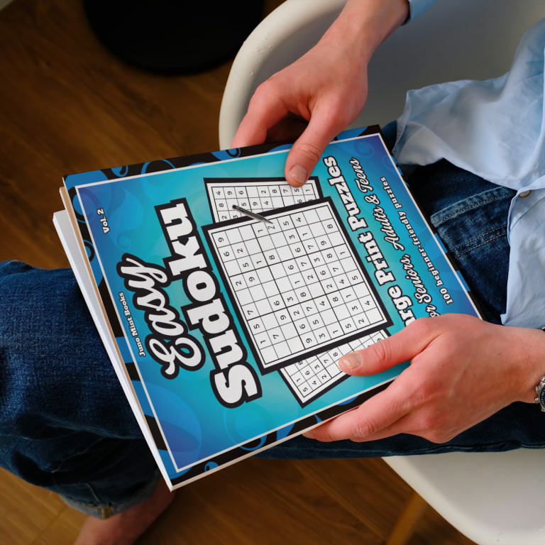 A man holding the Easy Sudoku Large Print Puzzles book by Juno Mint Books on his lap