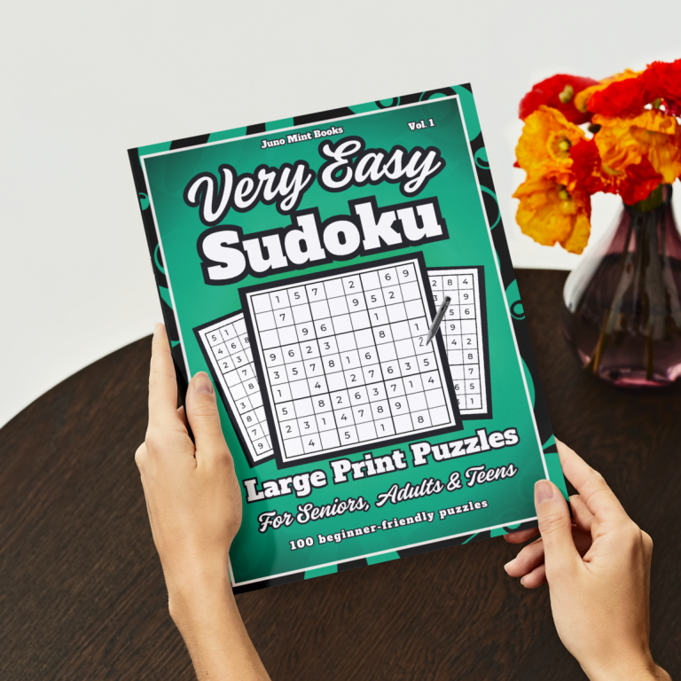 Person holding a Very Easy Sudoku Large Print Puzzle Book while sitting at a table.